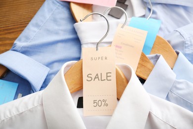 Image of Sale tag on wooden hanger with white shirt, closeup