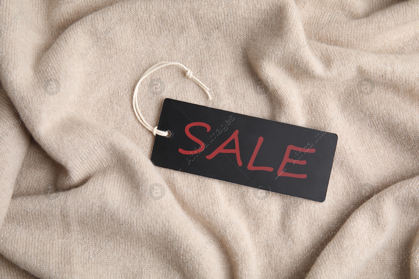 Black Sale tag on beige sweater, top view Image of Black Sale tag on beige sweater, top view