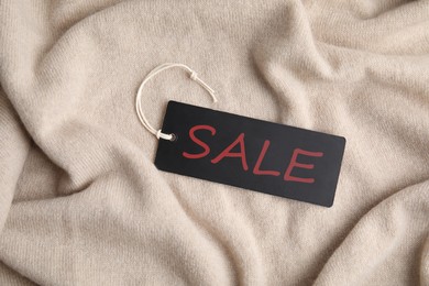 Image of Black Sale tag on beige sweater, top view