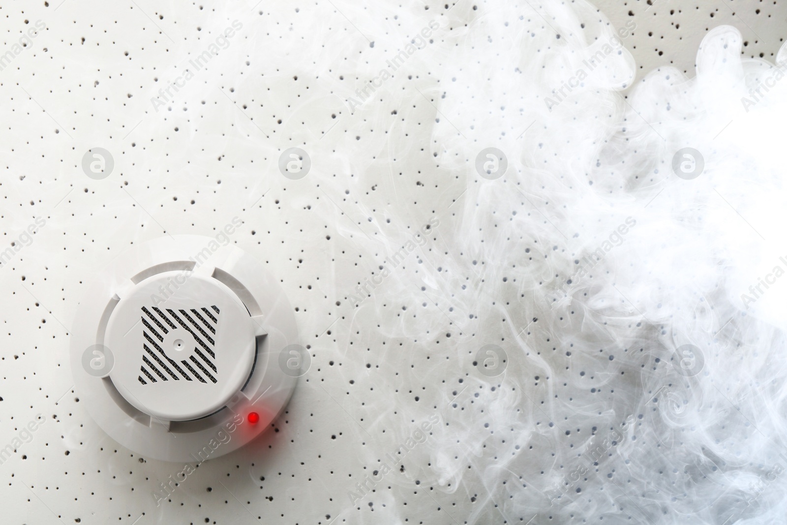 Fire alarm system detector on ceiling triggered by smoke, bottom view Image of Fire alarm system detector on ceiling triggered by smoke, bottom view