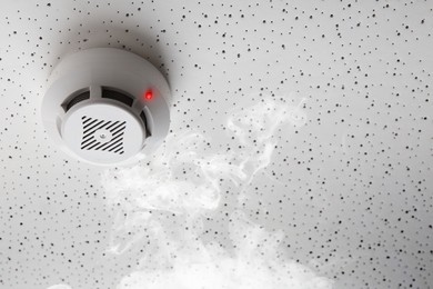 Image of Fire alarm system detector on ceiling triggered by smoke
