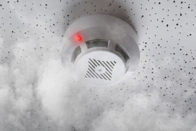 Image of Fire alarm system detector on ceiling triggered by smoke