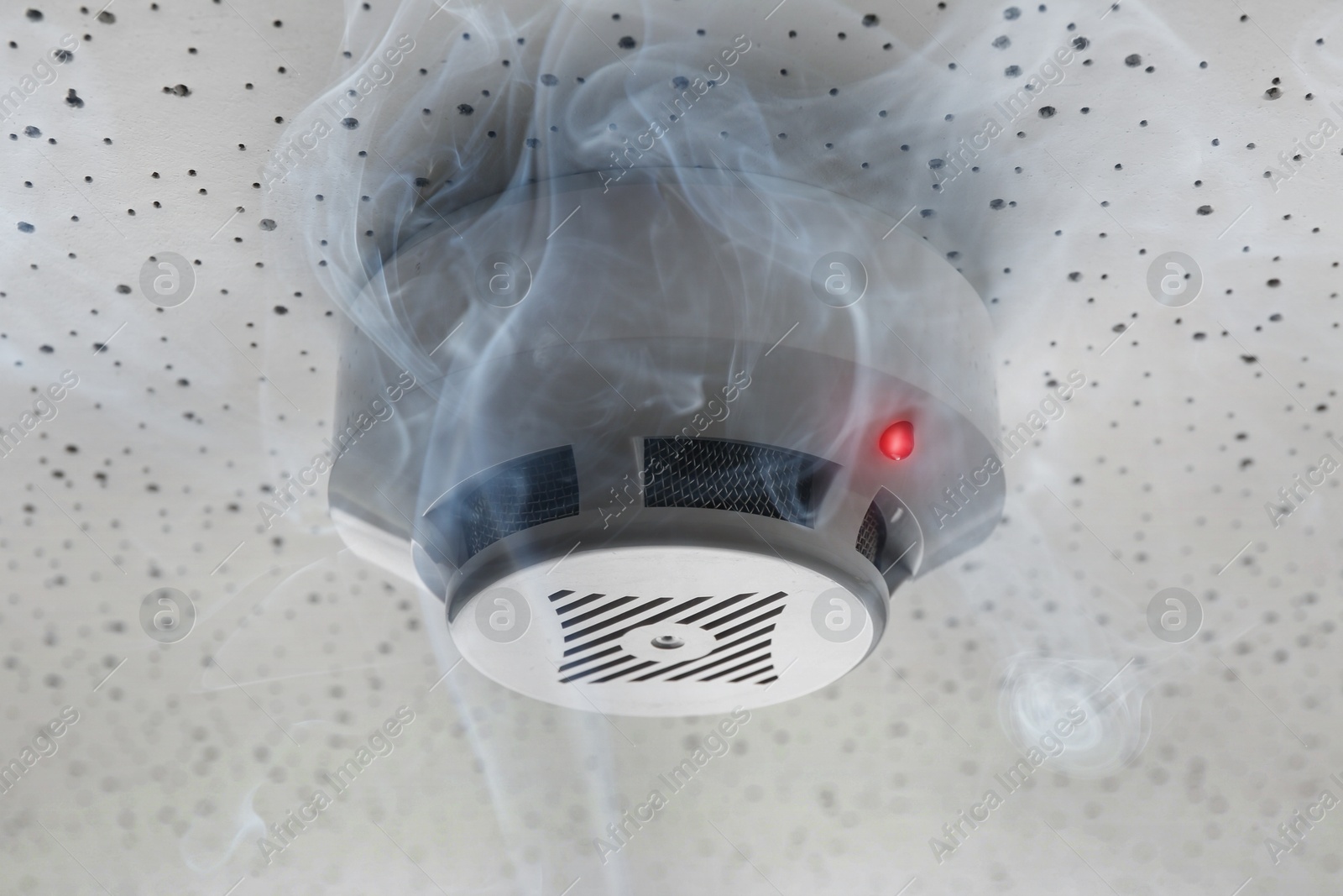 Fire alarm system detector on ceiling triggered by smoke Image of Fire alarm system detector on ceiling triggered by smoke