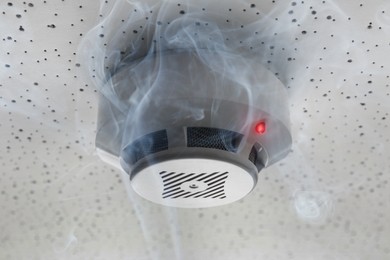 Image of Fire alarm system detector on ceiling triggered by smoke