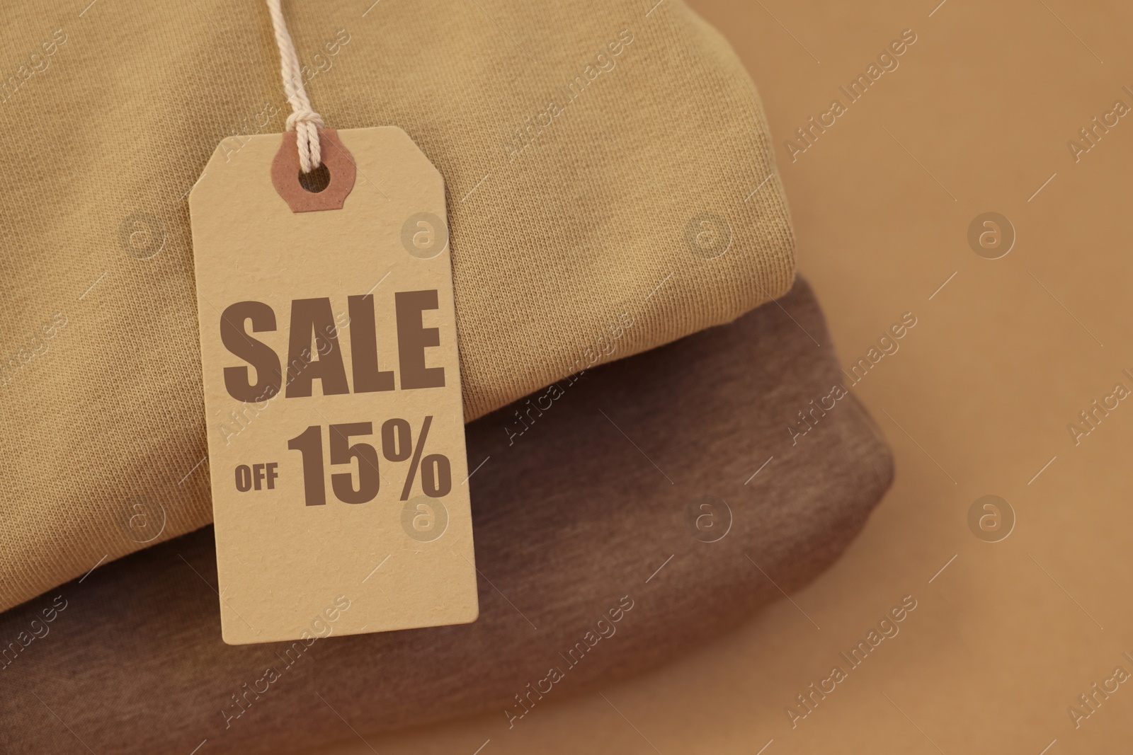 Sale tag and clothes on pale brown background, closeup Image of Sale tag and clothes on pale brown background, closeup