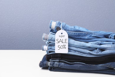 Image of Sale tag and stack of jeans on white table
