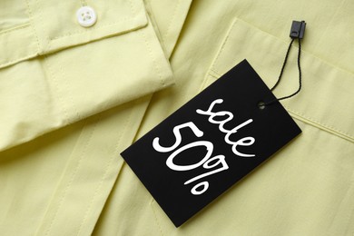 Image of Black Sale tag on light green shirt, top view