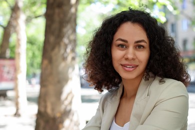 Photo of Portrait of smiling Latin American woman outdoors. Space for text