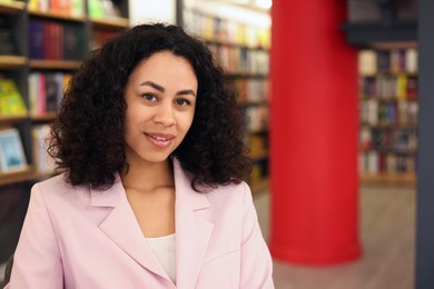 Photo of Portrait of smiling Latin American woman in bookshop. Space for text