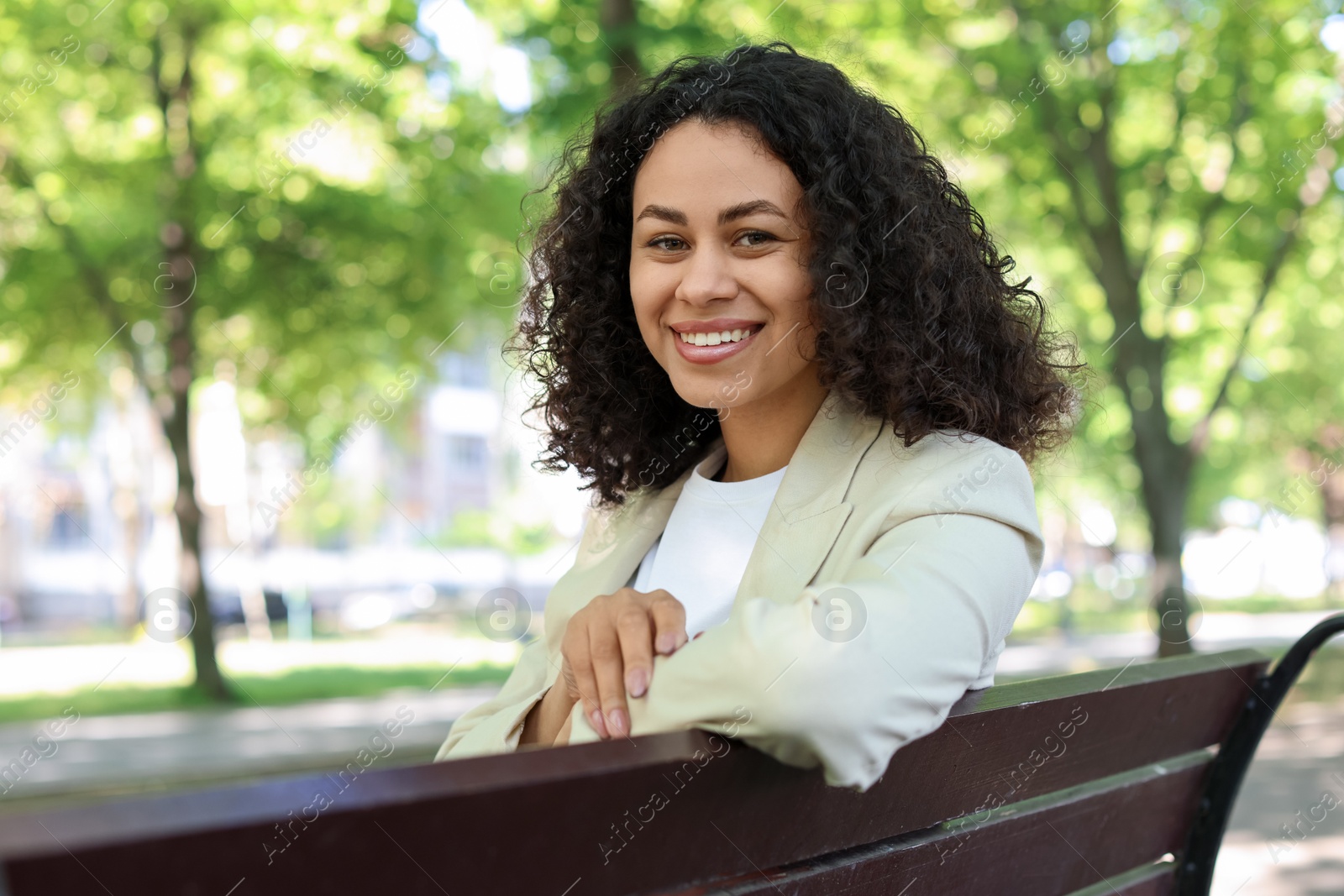 Portrait of smiling Latin American woman on bench outdoors Photo of Portrait of smiling Latin American woman on bench outdoors
