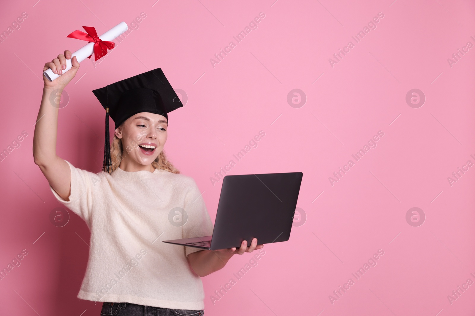Happy student with diploma and laptop after graduation on pink background. Space for text Photo of Happy student with diploma and laptop after graduation on pink background. Space for text