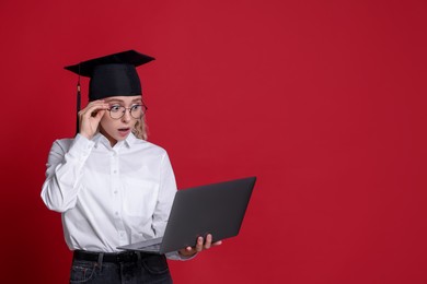 Photo of Excited student with laptop before graduation on red background. Space for text