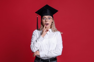 Photo of Emotional student after graduation on red background