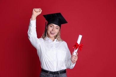 Photo of Happy student with diploma after graduation on red background