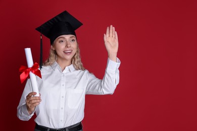Photo of Happy student with diploma waving after graduation on red background. Space for text