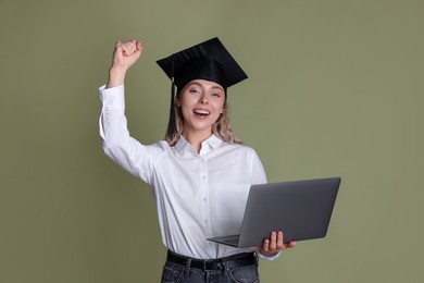 Photo of Happy student with laptop after graduation on green background