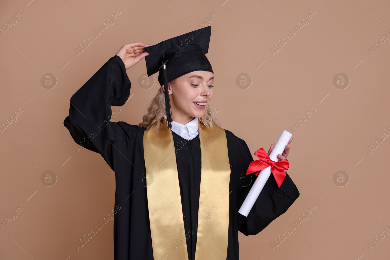 Happy student with diploma after graduation on beige background Photo of Happy student with diploma after graduation on beige background