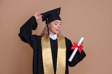 Photo of Happy student with diploma after graduation on beige background