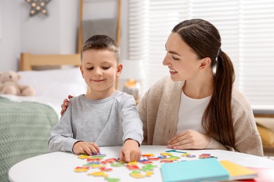 Photo of Dyslexia. Mother and her son learning letters at table indoors