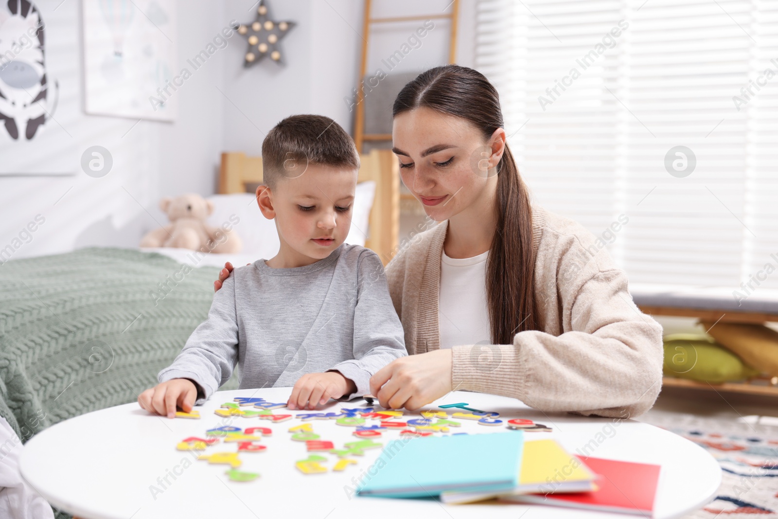 Dyslexia. Mother and her son learning letters at table indoors Photo of Dyslexia. Mother and her son learning letters at table indoors