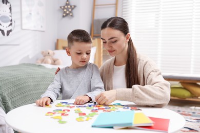 Photo of Dyslexia. Mother and her son learning letters at table indoors