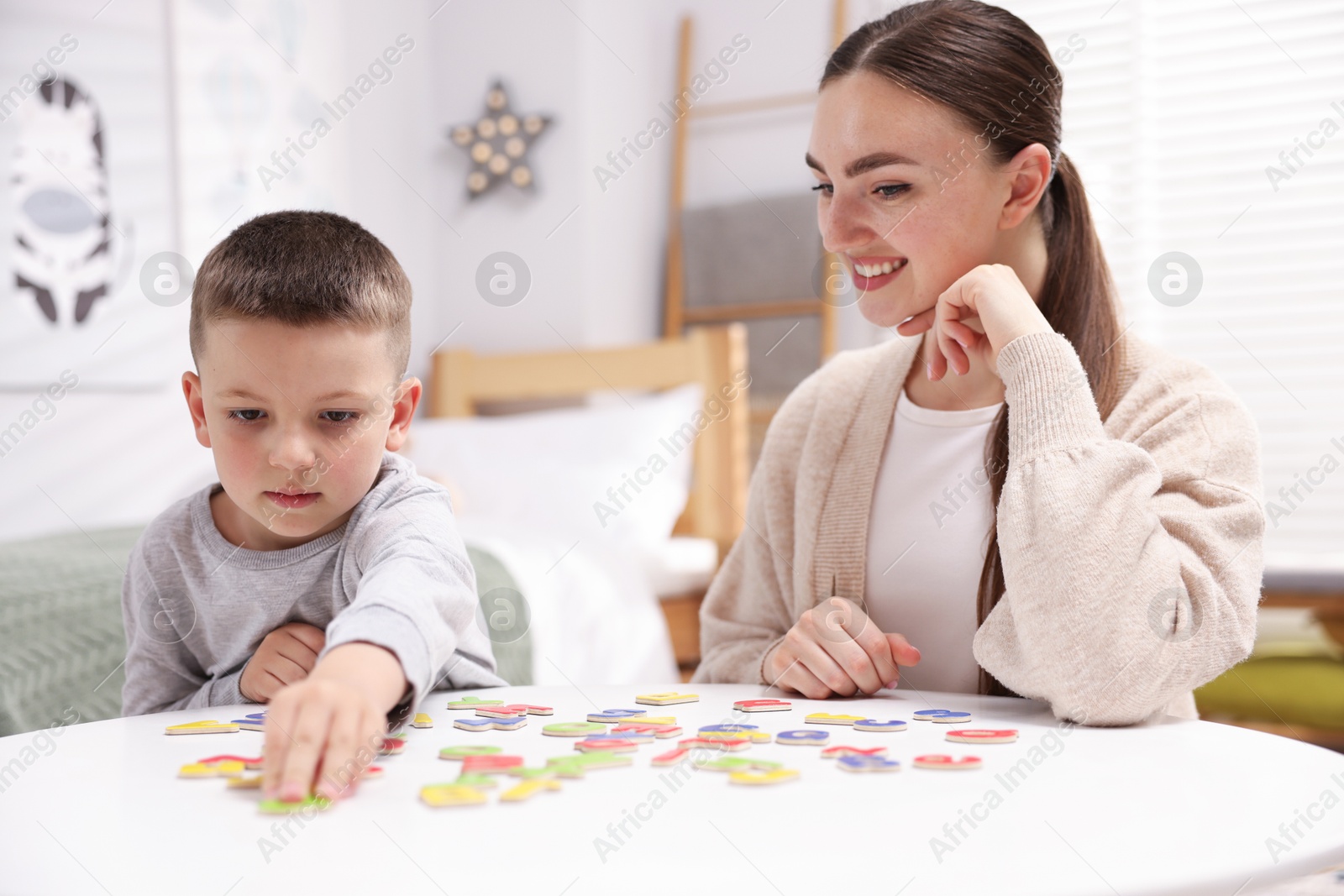 Dyslexia. Mother and her son learning letters at table indoors Photo of Dyslexia. Mother and her son learning letters at table indoors
