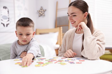 Photo of Dyslexia. Mother and her son learning letters at table indoors