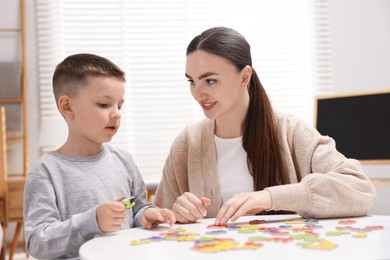 Photo of Dyslexia. Mother and her son learning letters at table indoors
