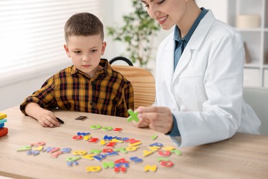 Photo of Dyslexia treatment. Pediatrician working with little boy at table indoors