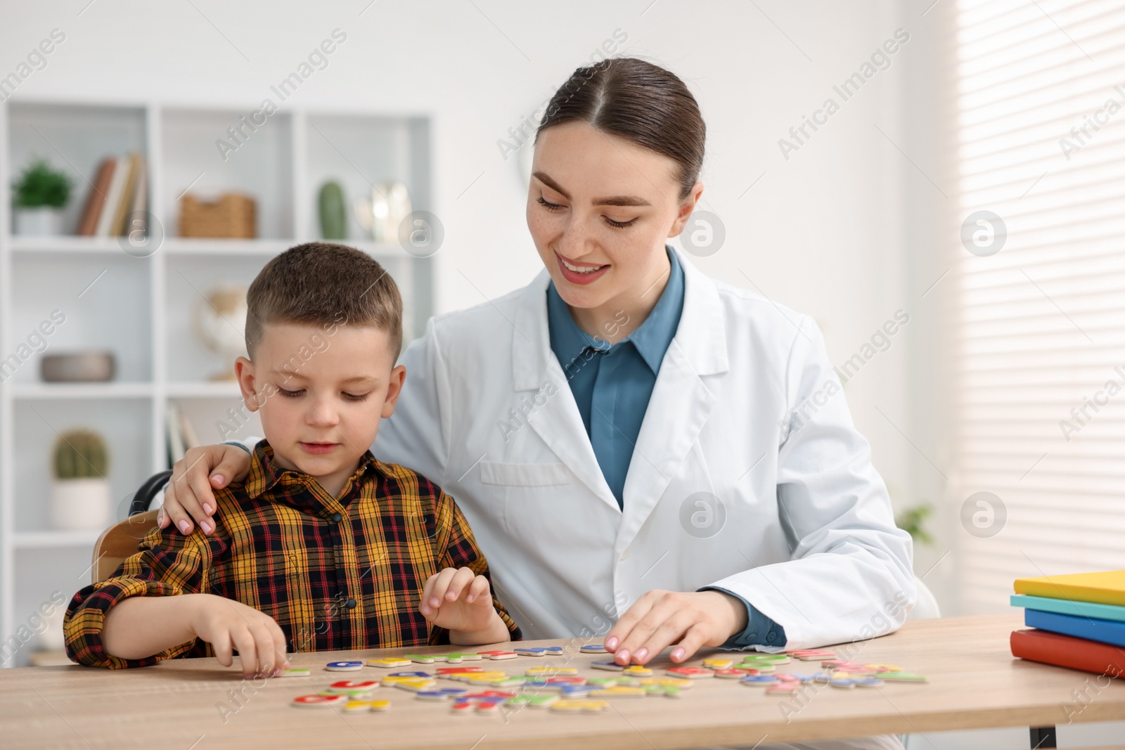 Dyslexia treatment. Pediatrician working with little boy at table indoors Photo of Dyslexia treatment. Pediatrician working with little boy at table indoors