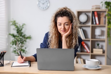 Photo of Woman working with laptop at desk in home office