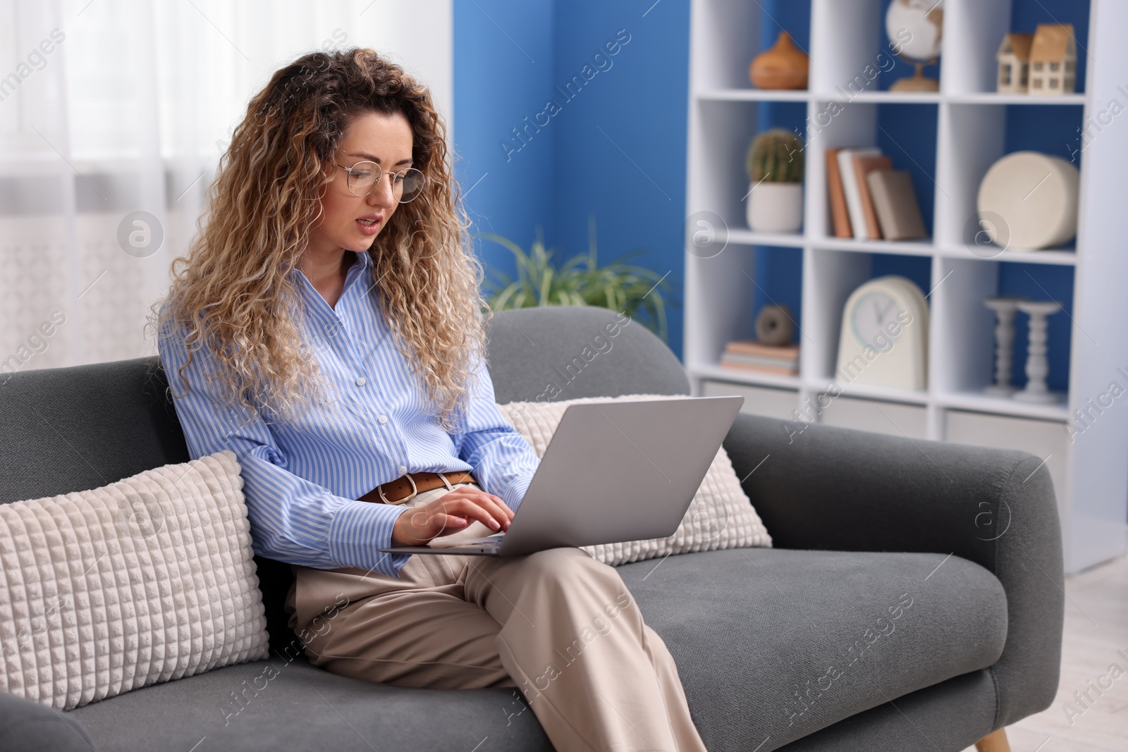 Woman working with laptop on sofa in home office Photo of Woman working with laptop on sofa in home office