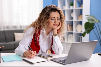 Photo of Woman working with laptop at desk in home office