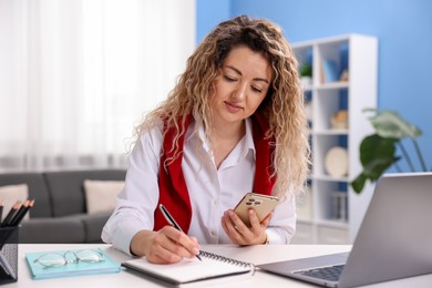 Photo of Woman with smartphone working at desk in home office