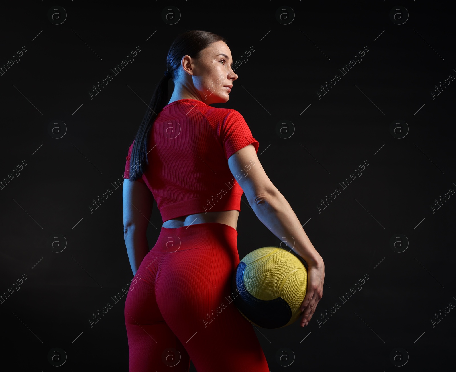 Photo of Woman with medicine ball on black background