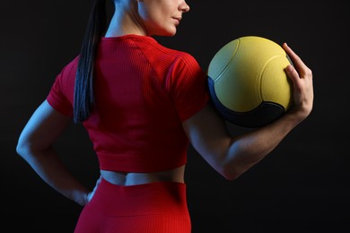 Photo of Woman with medicine ball on black background, closeup