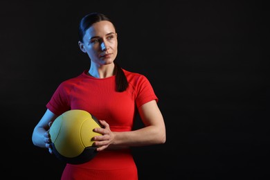 Photo of Woman with medicine ball on black background. Space for text
