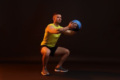 Photo of Man exercising with medicine ball on black background