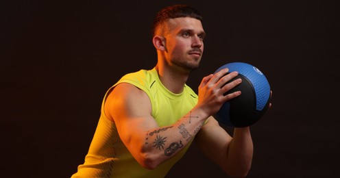 Photo of Man with medicine ball on black background