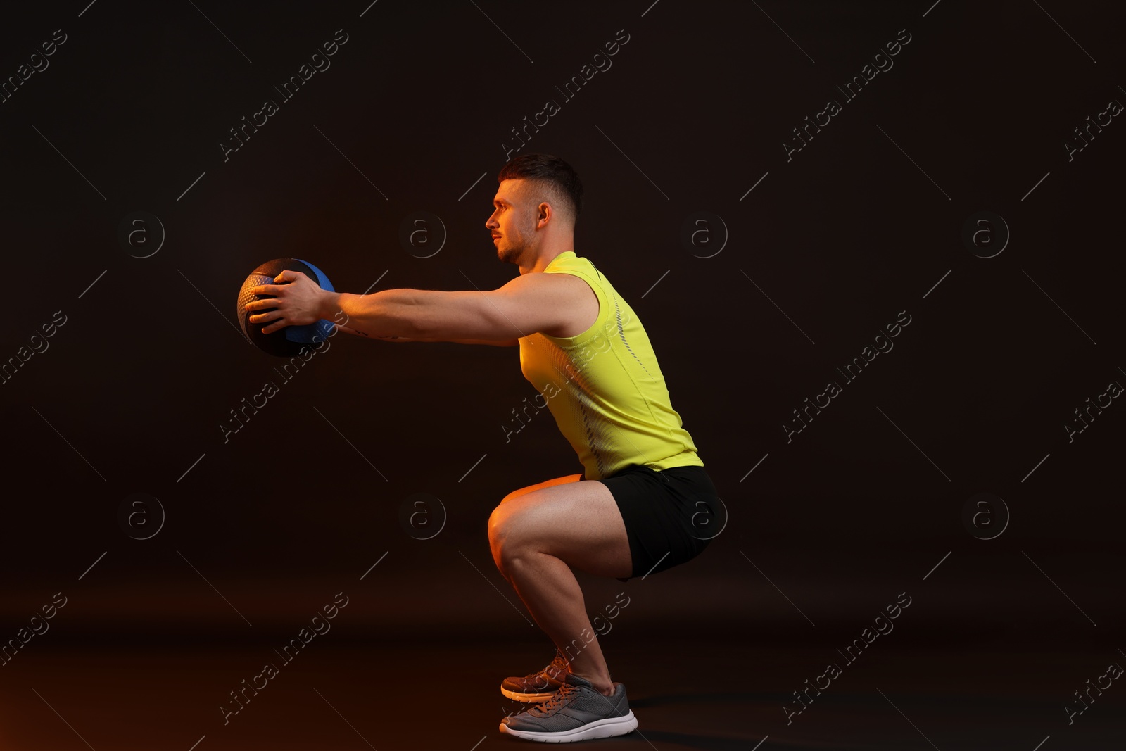 Man exercising with medicine ball on black background Photo of Man exercising with medicine ball on black background