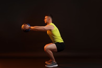 Photo of Man exercising with medicine ball on black background