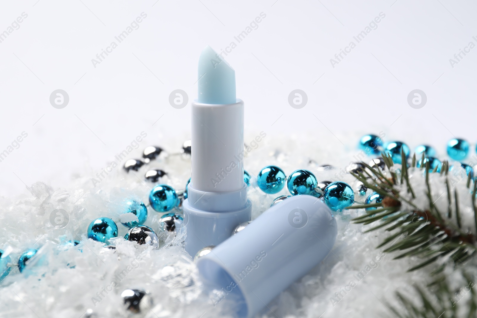 Moisturizing lip balm, Christmas decor and fir tree branches on artificial snow, closeup. Winter care Photo of Moisturizing lip balm, Christmas decor and fir tree branches on artificial snow, closeup. Winter care