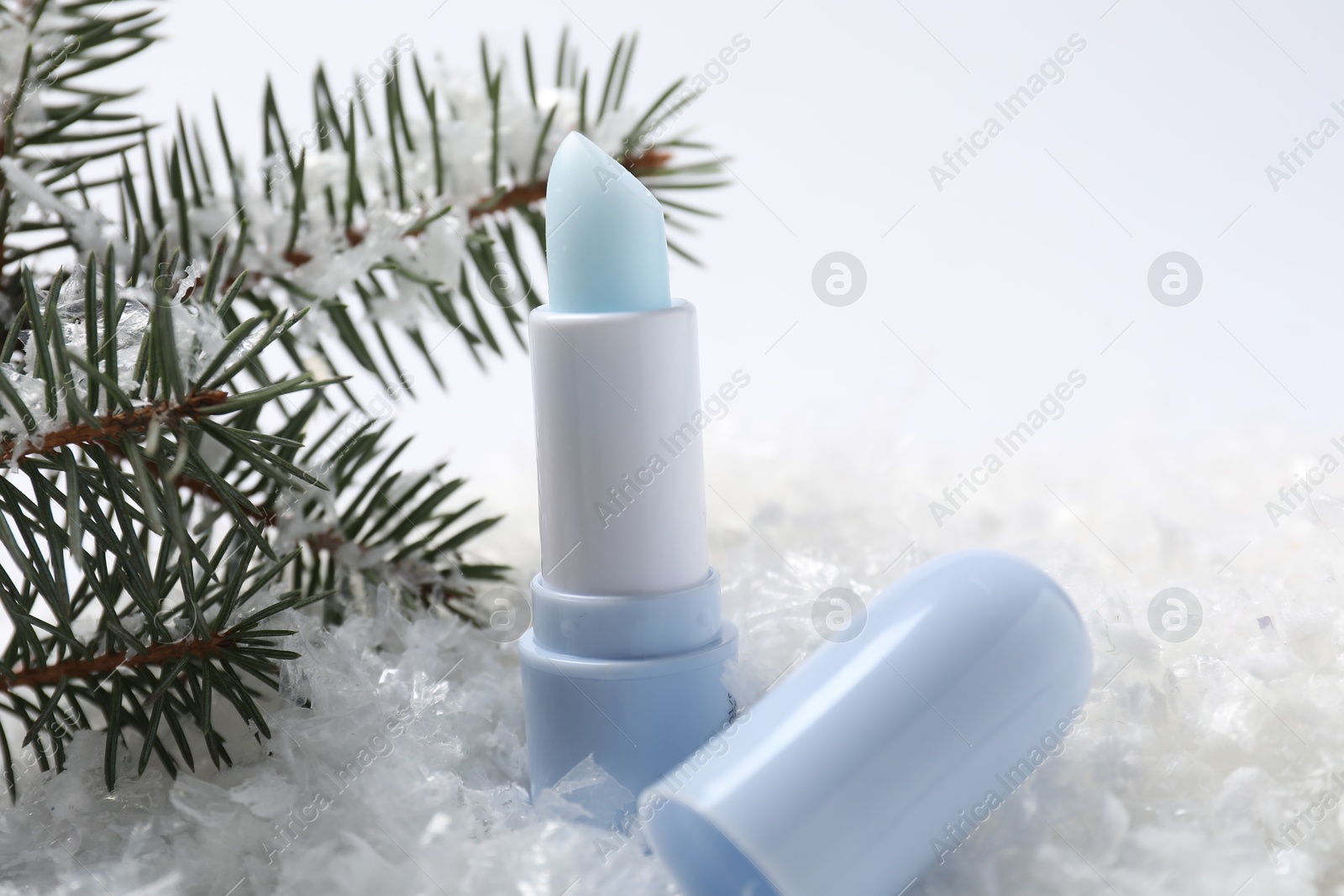 Moisturizing lip balm and fir tree branches on artificial snow, closeup. Winter care Photo of Moisturizing lip balm and fir tree branches on artificial snow, closeup. Winter care