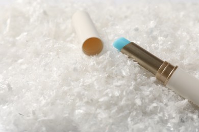 Photo of Moisturizing lip balm on artificial snow, closeup. Space for text