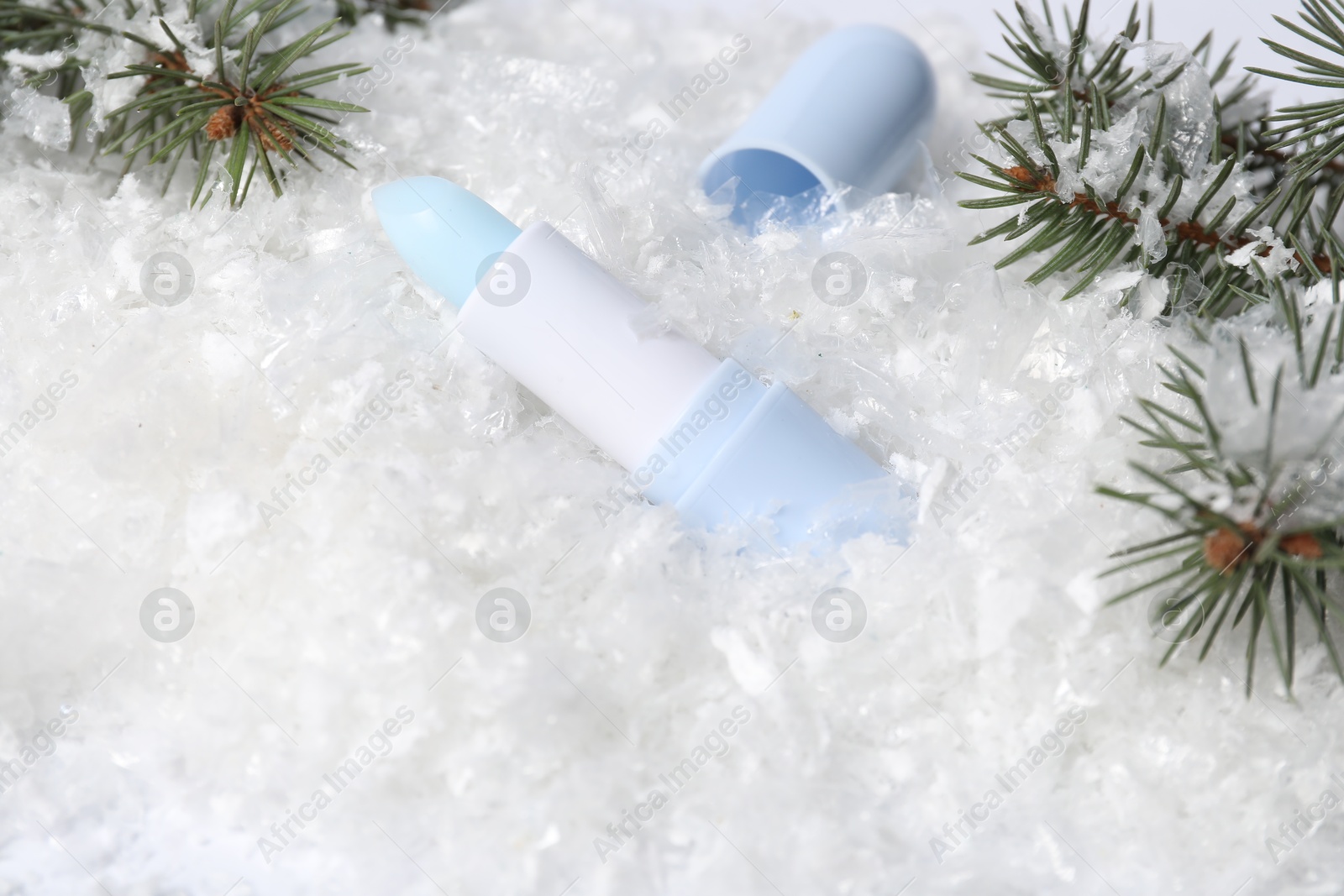 Moisturizing lip balm and fir tree branches on artificial snow, closeup. Winter care Photo of Moisturizing lip balm and fir tree branches on artificial snow, closeup. Winter care