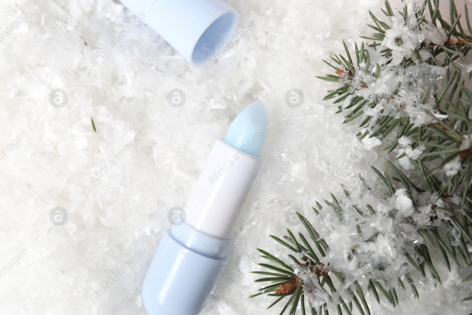 Moisturizing lip balm and fir tree branches on artificial snow, flat lay. Winter care Photo of Moisturizing lip balm and fir tree branches on artificial snow, flat lay. Winter care