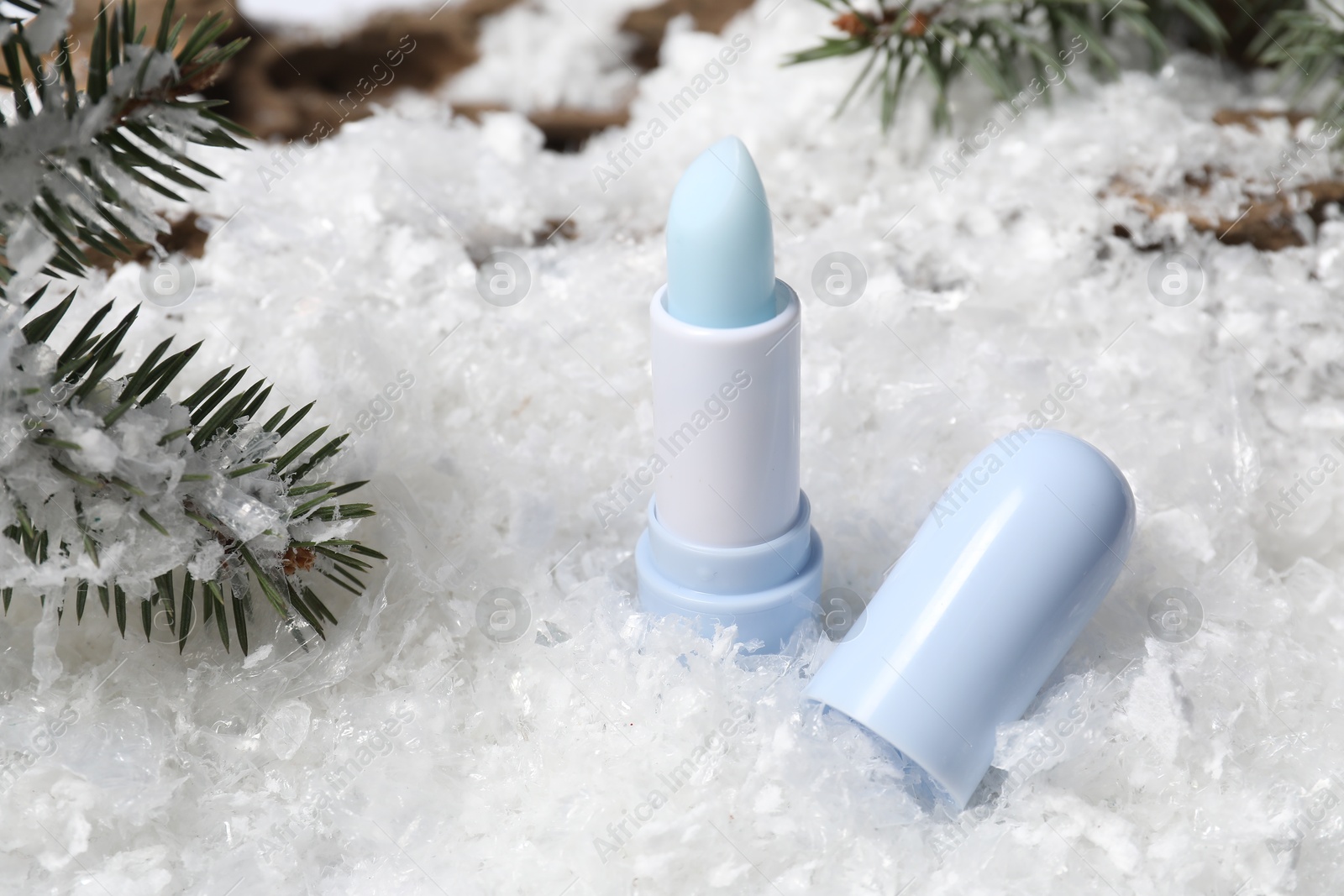 Moisturizing lip balm and fir tree branches on artificial snow, closeup. Winter care Photo of Moisturizing lip balm and fir tree branches on artificial snow, closeup. Winter care