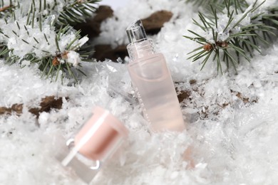 Photo of Moisturizing lip balm and fir tree branches on artificial snow, closeup. Winter care