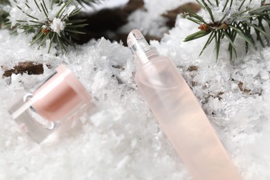 Photo of Moisturizing lip balm and fir tree branches on artificial snow, closeup. Winter care