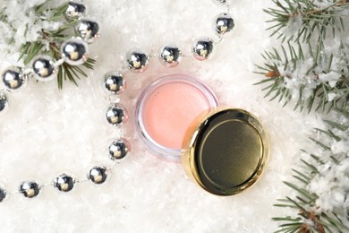 Photo of Moisturizing lip balm, Christmas decor and fir tree branches on artificial snow, flat lay. Winter care